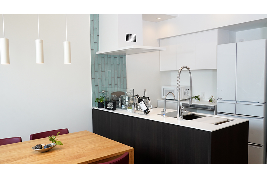 白の人工大理石カウンターと淡緑のウオール・タイルのシックな組み合わせ