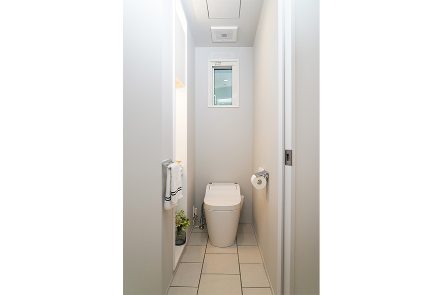 淡グレーの床・壁・天井に白い便器・手洗いニッチ浮き上がるシックな空間構成